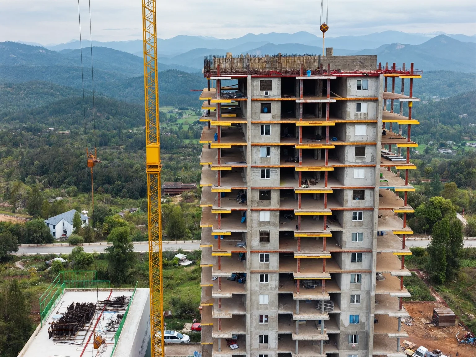 Aerial drone photo of a concrete residential tower under construction with a tower crane (AI-generated sample image)