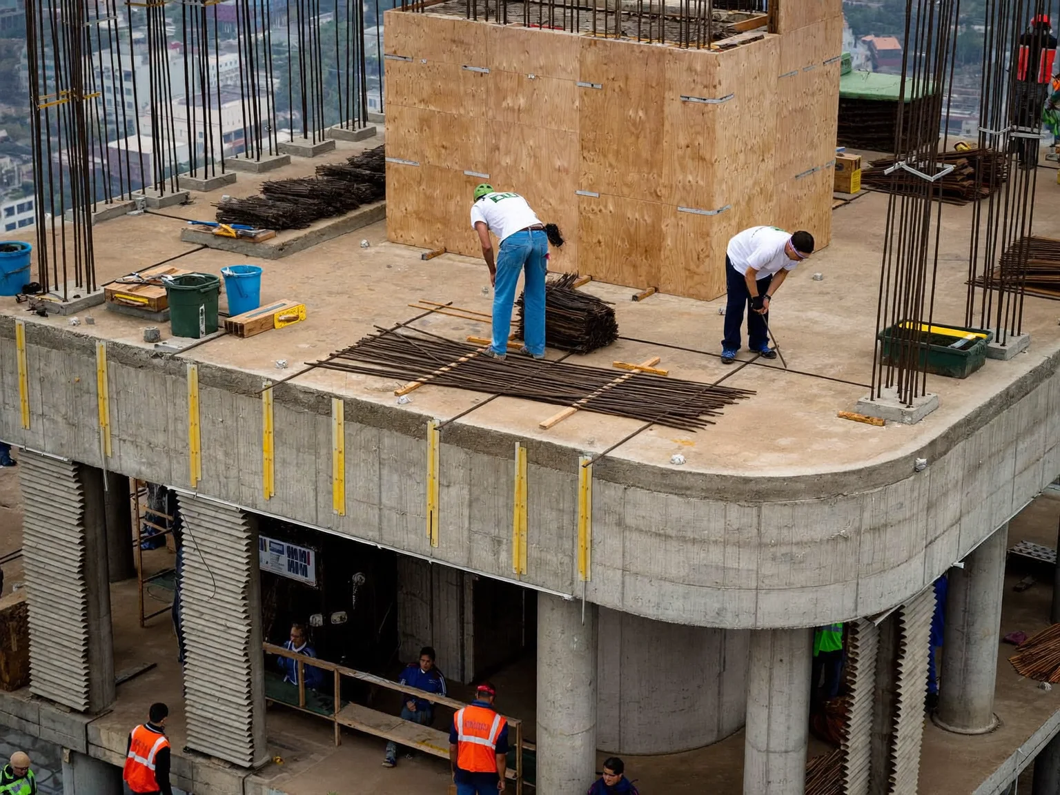 Workers tying rebar on the top deck of a concrete tower (AI-generated sample image)
